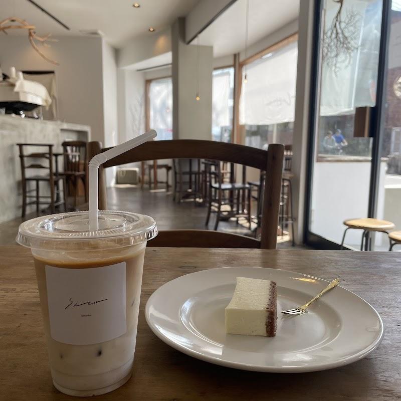 A serene cafe scene features an iced latte with a "Siro" label and a slice of layered cake on a wooden table. The bright, minimalist cafe decor includes light wood furniture and large windows, creating a calm and inviting atmosphere.